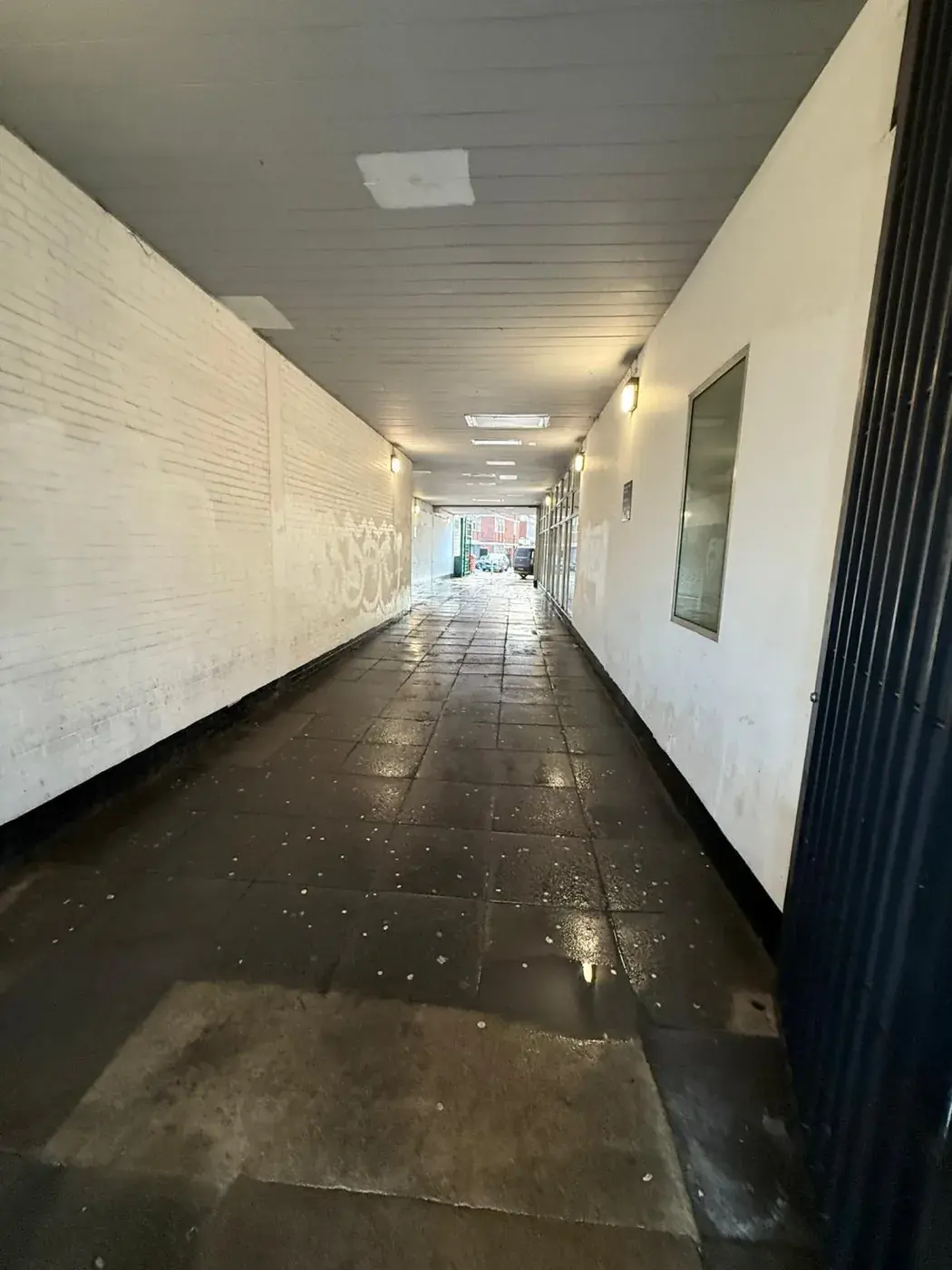 A covered walkway between buildings, tiled floor washed down and still wet