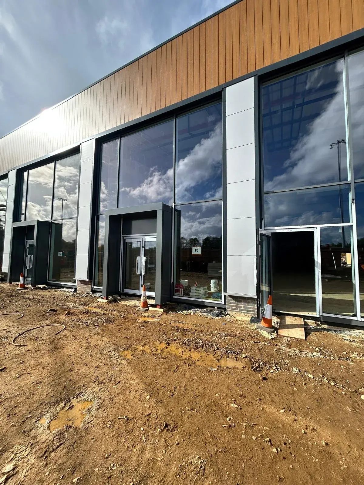 A new commercial unit with full height glazing, cones and bare earth still outside