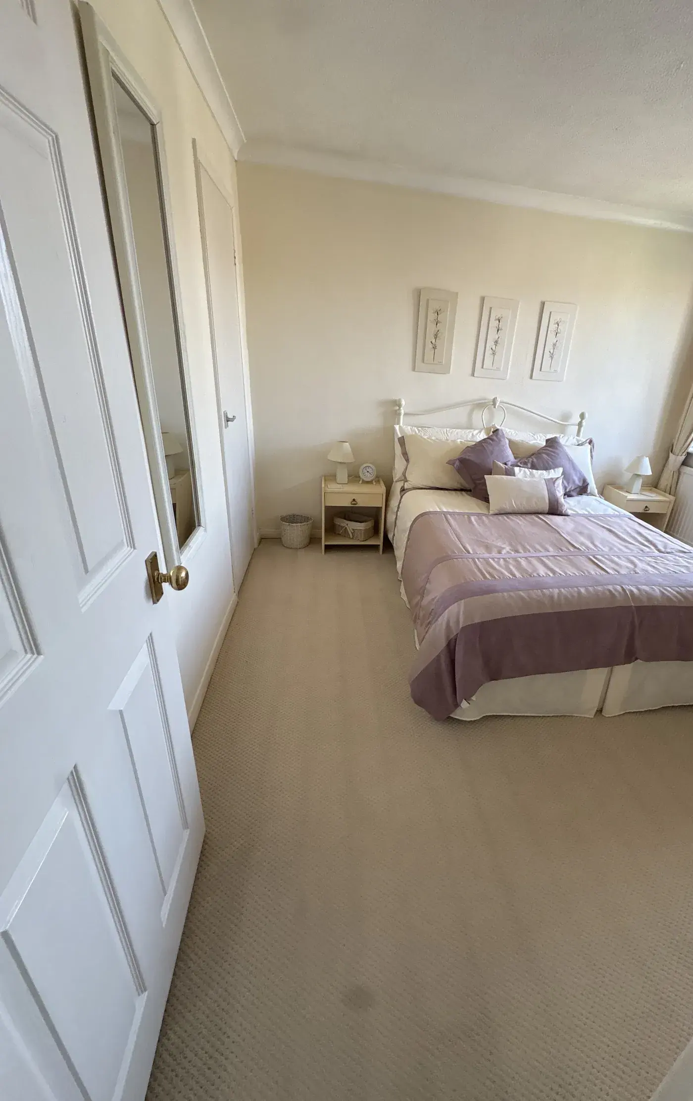 A double bedroom with the bed made and the cream carpet freshly vacuumed