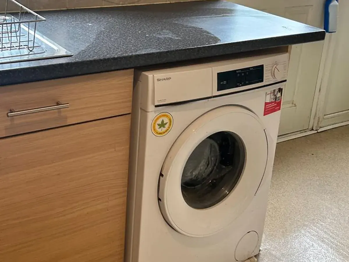 A kitchen corner cleared and wiped down, worktop, sink and washing machine left empty