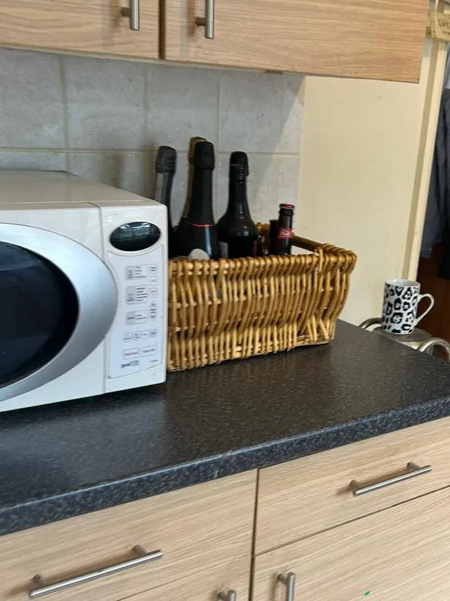 Kitchen worktop with microwave, wicker basket of bottles and a mug, cleared and wiped