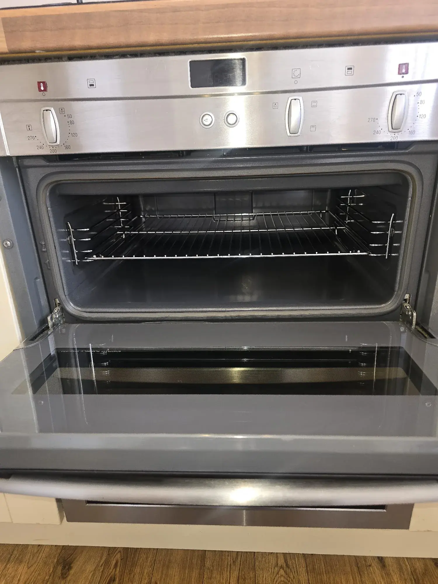 A built in oven with the door open, showing the racks and interior after cleaning