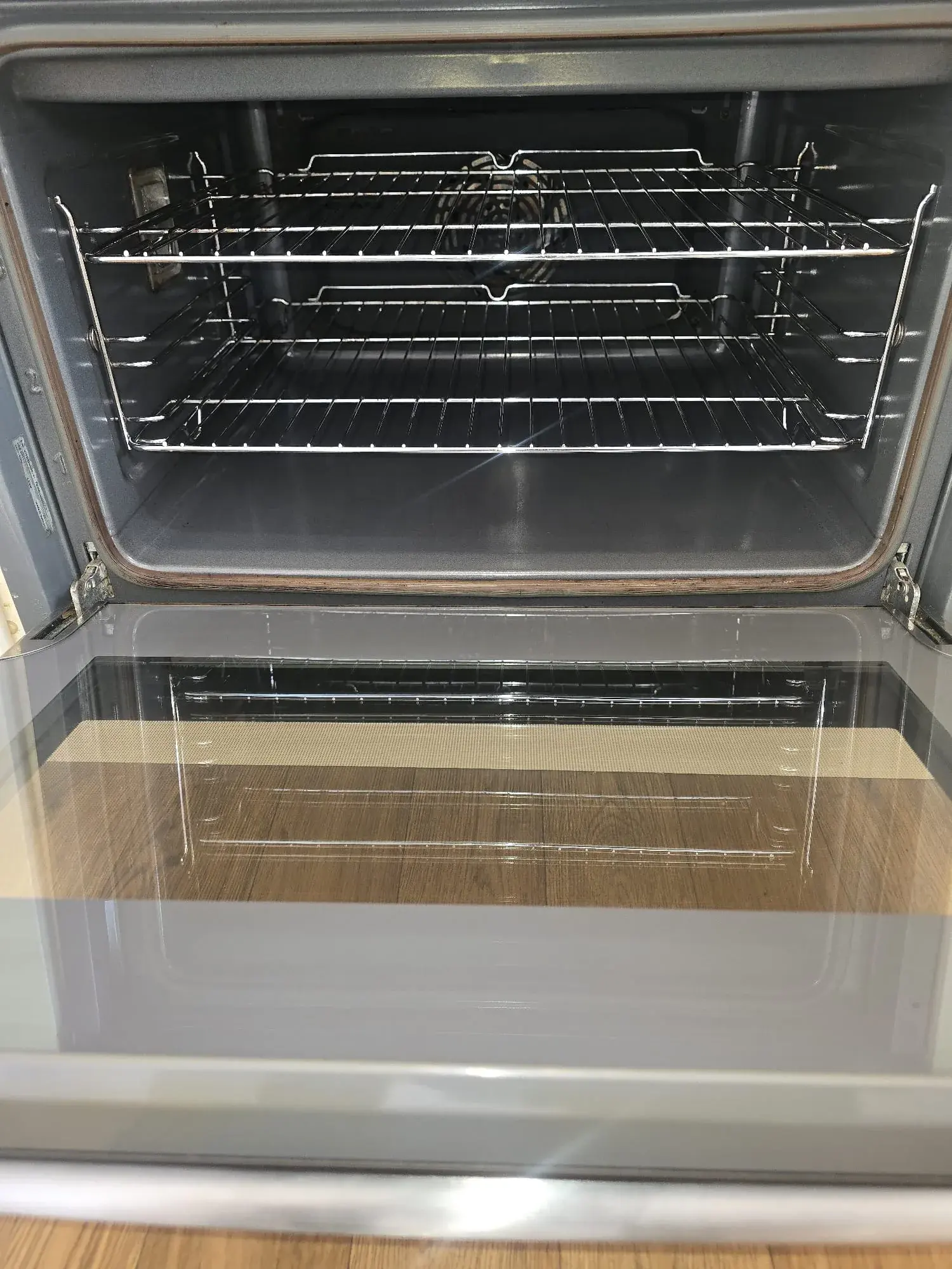 A single oven with the door down, wire shelves and interior washed clean