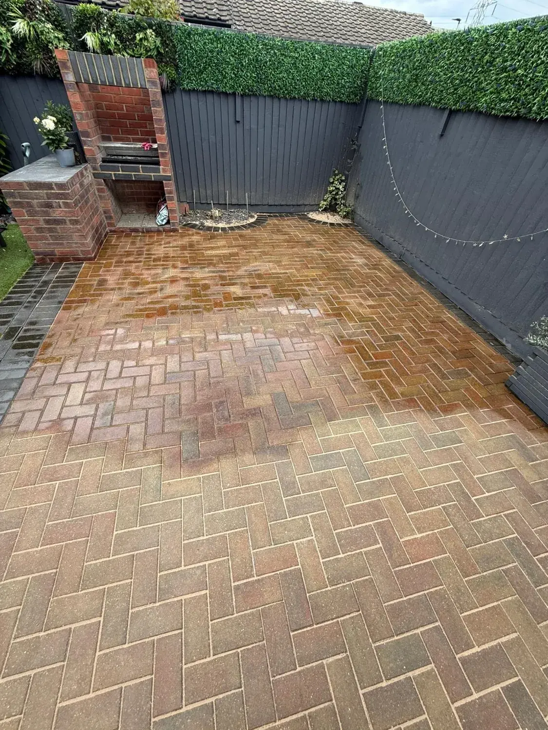 Patio part way through a jet wash, the back still green with algae and the foreground washed clean