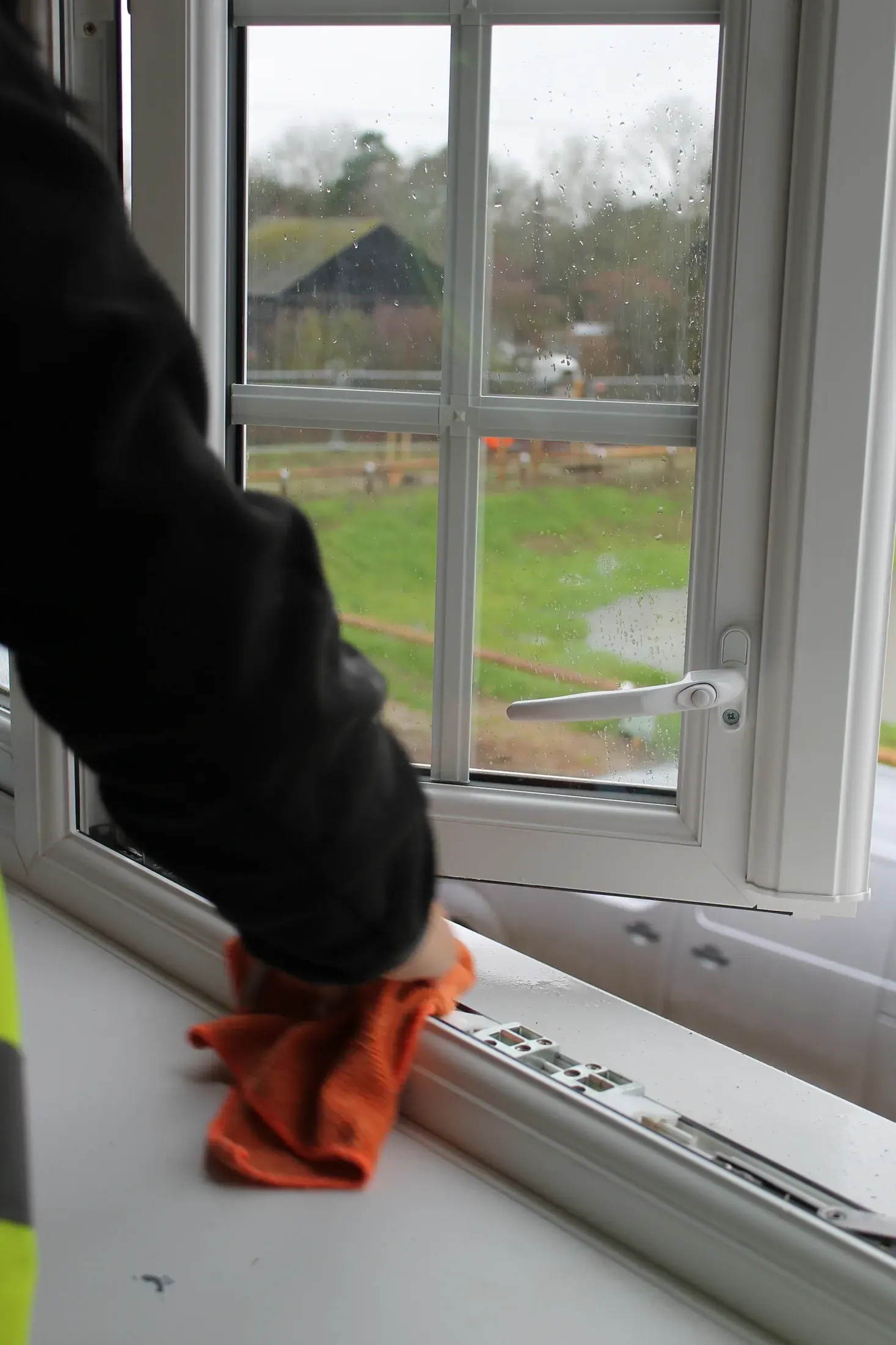 A window sill and frame being wiped down with an orange cloth